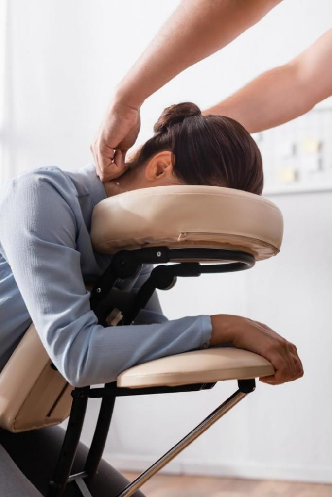 Massage habillé d'une femme sur un siège confortable dans un cadre apaisant